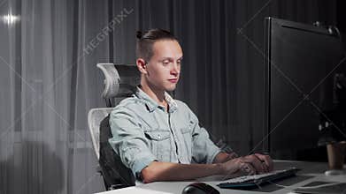 Happy man finishing work on his computer late at night