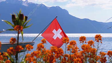 Swiss flag on a background of alpine mountains and flowers near lake Geneva