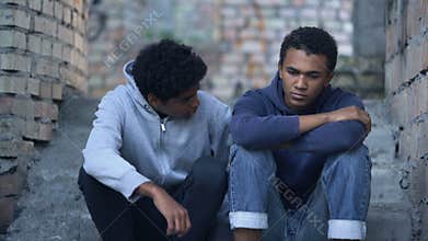 African student hugging sad friend sitting stairs, friendship support, problem