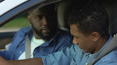 Nervous father giving slap upside head to son, trying to drive car, anxiety