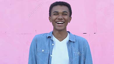 Happy afro-american boy laughing on pink background, enjoying carefree youth