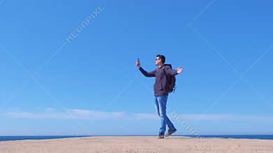 Young man tourist traveller blogger talking video chat walking at sea pier.
