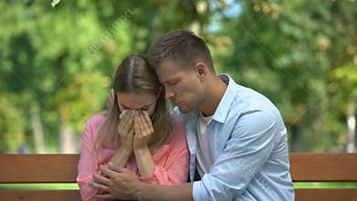 Man hugging and supporting crying wife in park, relative death, togetherness