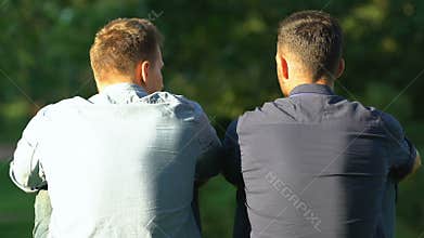 Two best friends sitting outdoor discussing life problems, friendship, back-view