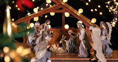 Jesus Christ Nativity scene with atmospheric lights near Christmas tree