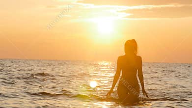 Silhouette figure of a woman coming out from the water in a swimsuit at dawn, a girl swimming in the sea enjoying sunrise, the con