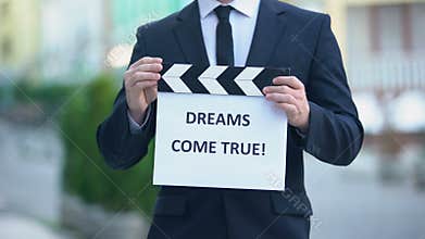 Dreams come true phrase on clapperboard in hands of producer, cinematography