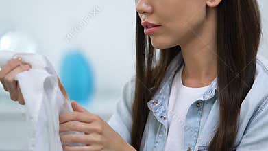 Unhappy young woman looking at coffee stain on blouse, ineffective spot remover