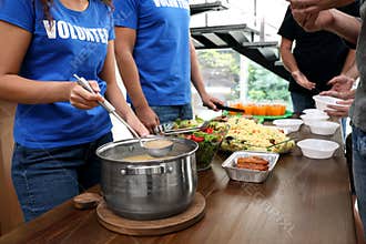 Volunteers serving food to  people in charity centre, closeup