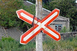 Traffic sign a white cross with a red outline pinned to a pillar against the background of an old house.