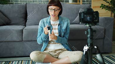 Female blogger recording video about digital watch using camera in apartment