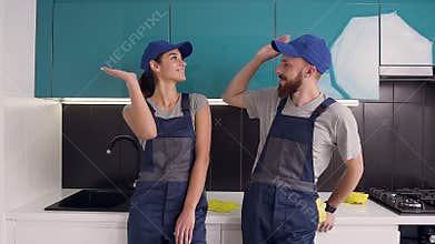 Happy satisfied their work man and woman of the cleaning service giving high five in the blue-black cuisine