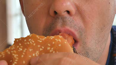 Man eating a hamburger. close-up shot. Fast food eats. Close up of man eating burger.