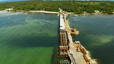 Construction of a bridge across the bay. Construction equipment on the bridge, top view. Siargao, Philippines.