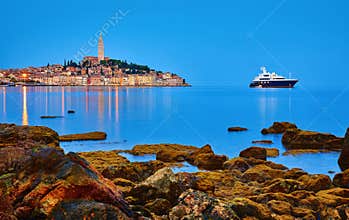 Rovinj, Croatia. Antique medieval old town nighttime view. Luxury yacht and fishing sea. Big stones
