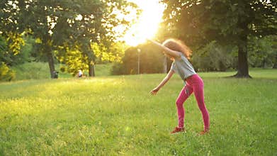 Little Girl Having Fun On The Green Grass While Making a Acrobatic Wheel. Young Sporty Kid Has a Really Good Mood.