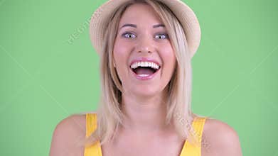 Face of happy young blonde tourist woman looking surprised