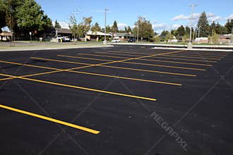 Newly painted yellow stripes create parking stalls in a new parking lot.