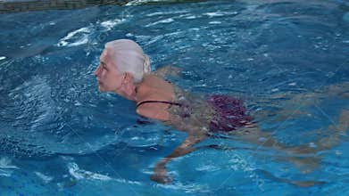 Happy elderly woman swimming in pool of spa hotel