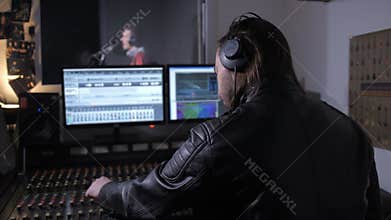 Music producer in headphones working on soundboard