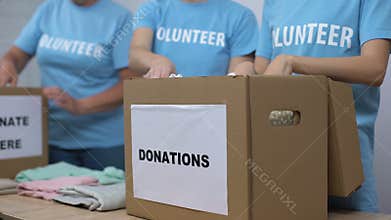 Social center volunteers putting clothes in donation boxes, altruism generosity