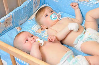 Two babies lying in wooden crib