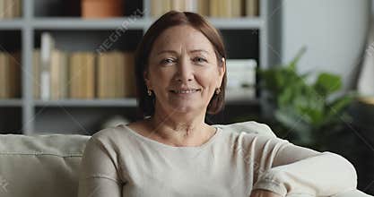 Smiling older adult lady looking at camera posing at home