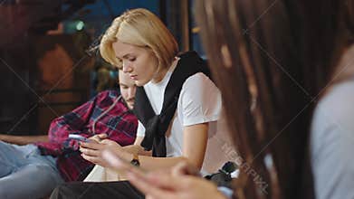 Good looking group of students closeup to the camera sitting on their phones in the college library