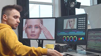 Freelance videographer colorist editing footage using professional software, monitor and montage console.