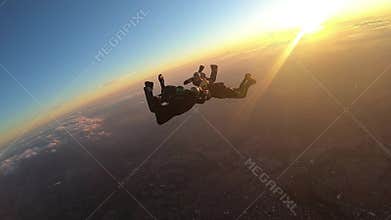 Skydivers make a formation skydive at the sunset