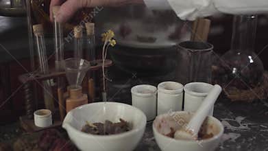 Close-up of Caucasian male hand touching ancient test tubes. Mortar and pestle standing at the table with different