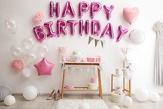 Phrase HAPPY BIRTHDAY made of pink balloon letters in room