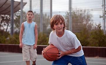 Kids play basketball in a school.