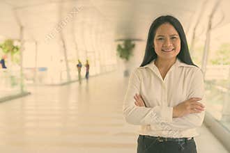 Mature beautiful Asian businesswoman relaxing at the footbridge in the city