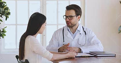 Happy male doctor handshake female patient at medical consultation