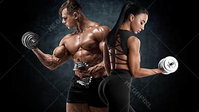 Sporty couple workout with dumbbells. Muscular man and woman showing muscles