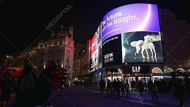 People and traffic in front of the famous digital billboards of Piccadilly Circus at night