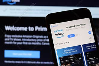 Los Angeles, California, USA - 27 November 2019: Amazon Prime Video app icon on mobile phone screen with blurry website on laptop