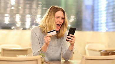 Excited woman buying online in a bar in the night