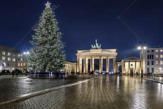 Night view to the Brandeburg Gate in Berlin, Germany, with a lit christmas tree in front