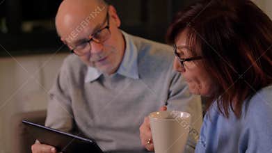 Senior couple with book and tablet pc at home