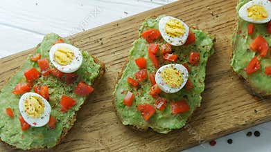 Healthy vegan food. Spread mashed avocado on toasted brown bread with black and red pepper. Making tasty avocado toast