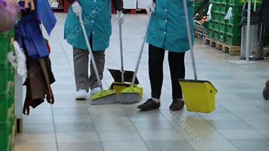 Cleaning service workers sweeping floor in supermarket