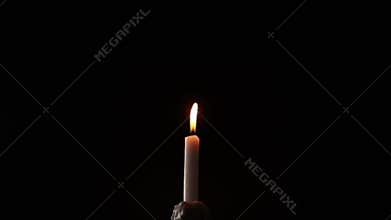 Gusts of wind trying to extinguish a candle on a black background.