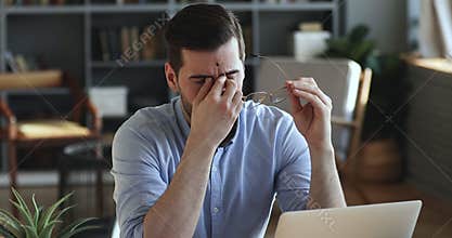 Exhausted businessman taking off glasses massaging dry irritated eyes