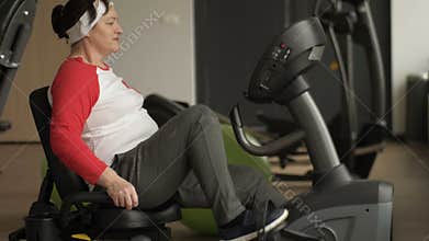 Middle aged woman with excess weight working out on stationary bike