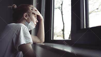 Woman with protection medical face mask by the window