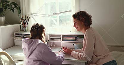 Happy adult parent mother helping teenage daughter doing homework
