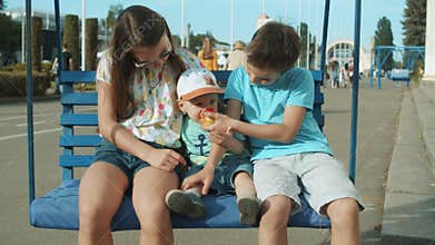 Cute three siblings riding on swing outdoor. Adorable kids spending time in park