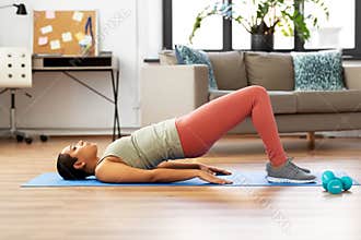 Woman doing pelvic lift abdominal exercise at home